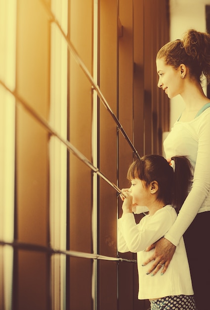 Smiling mother with her daughter looking through the window