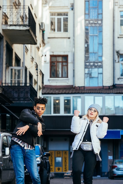 Улыбаясь много этнических молодая пара, стоя под зданием, танцы на улице