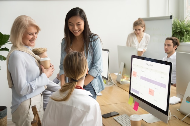 Smiling multiracial businesswomen colleagues of different age talking in office