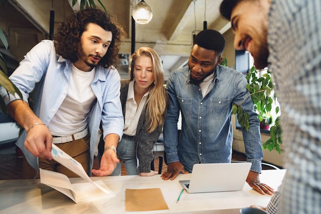 Smiling multiracial coworkers working together at office meeting have a discussion