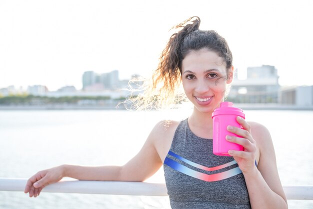 Smiling Nice Sporty Girl Drinking by City River