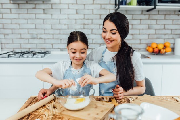 Smiling older sister with her smaller. Cook with eggs