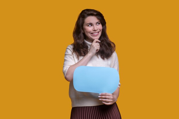 Smiling pensive holding a question sign and touching her chin