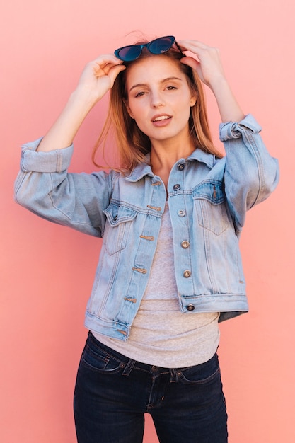 Smiling portrait of a beautiful young woman wearing sunglasses over her head looking at camera