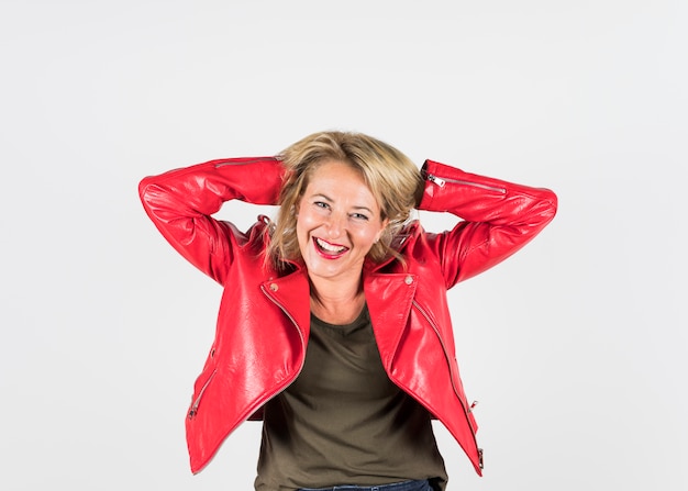 Smiling portrait of a blonde mature woman in red leather jacket standing against white background