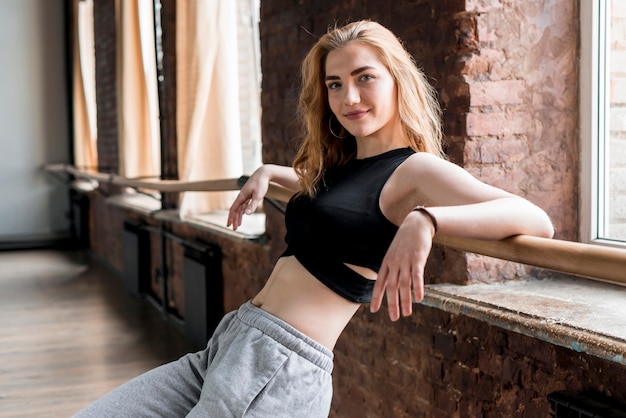 Smiling portrait of a blonde young woman leaning on barre