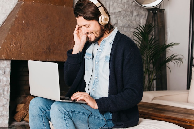 Foto gratuita ritratto sorridente di un uomo che per mezzo della compressa digitale per ascoltare musica sulla cuffia