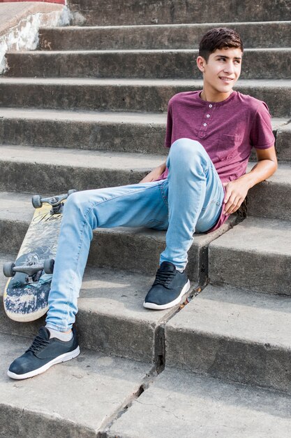 스케이트 보드와 계단에서 편안한 십대 소년의 웃는 초상화