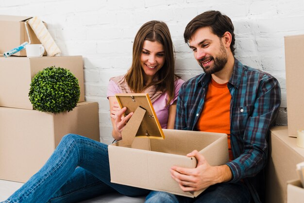 Smiling portrait of a young couple looking at frame taken from cardboard box