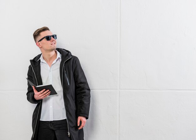 Smiling portrait of a young man holding book in hand looking away