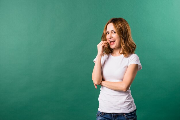 Smiling portrait of a young woman against green backdrop