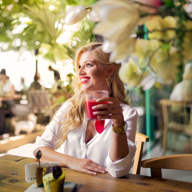 Улыбающийся портрет молодой женщины, держащей стакан сока в ресторане