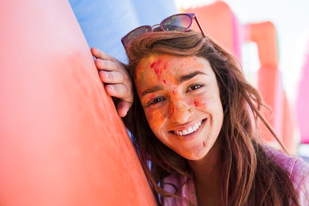 카메라를보고 얼굴 파우더에 holi 색상으로 젊은 여자의 웃는 초상화