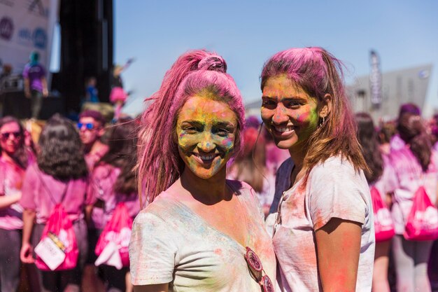 Smiling portrait of a young women with holi powder on their face looking at camera