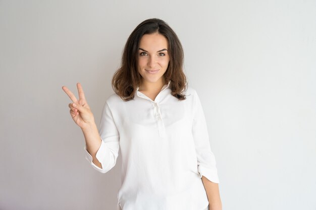 Smiling positive beautiful girl showing two fingers. 