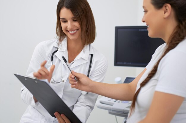 Smiling pregnant woman signing documents at clinic