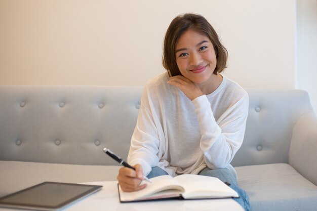 Усмехаясь милая азиатская женщина изучая дома