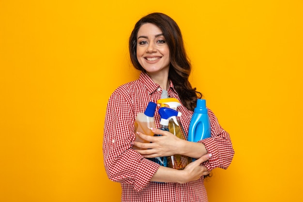 Smiling pretty caucasian cleaner woman holding cleaning sprays and liquids 
