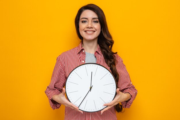 Smiling pretty caucasian cleaner woman holding clock and looking 