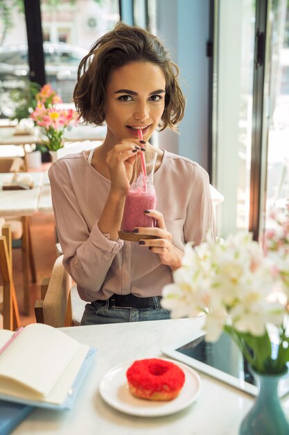 Улыбающаяся красивая девушка пьет коктейль с соломой
