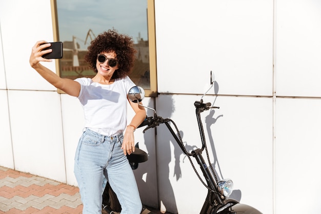 Smiling pretty girl in sunglasses taking a selfie