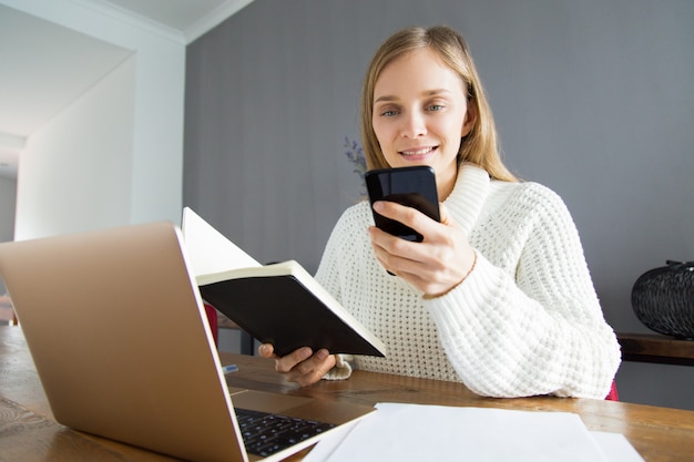 Smiling pretty lady checking timetable while texting sms