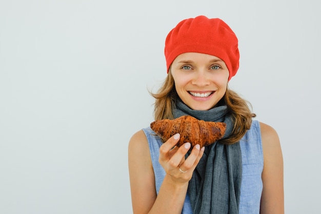 Smiling pretty woman holding delicious croissant