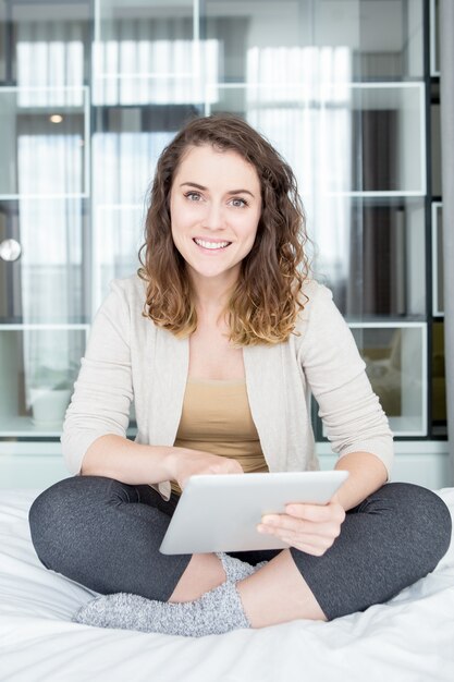 Free photo smiling pretty woman using tablet on bed