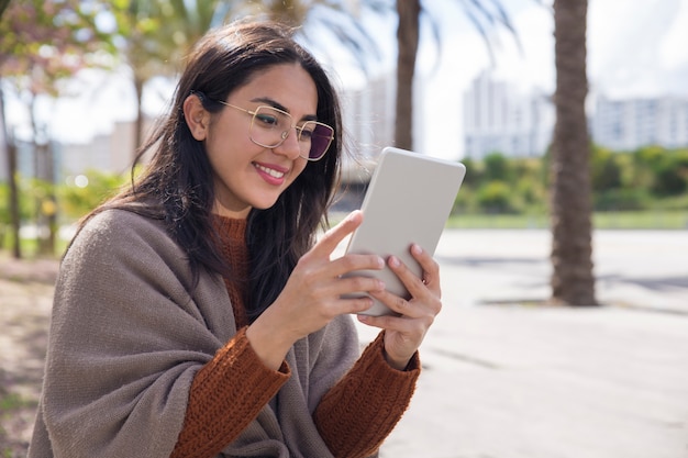 タブレットコンピューターを屋外で使うきれいな女性の笑みを浮かべてください。