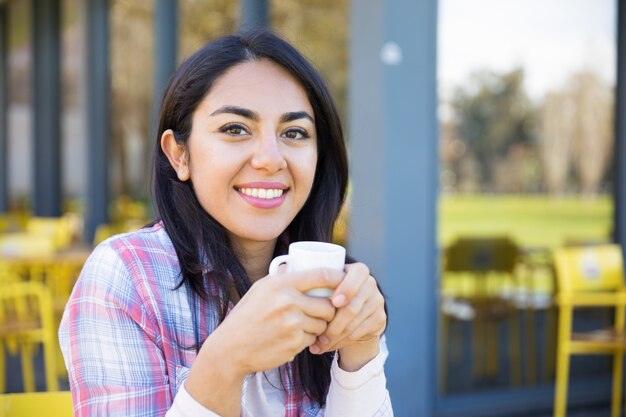 カフェでコーヒーを飲みながら楽しんで笑顔のかなり若い女性