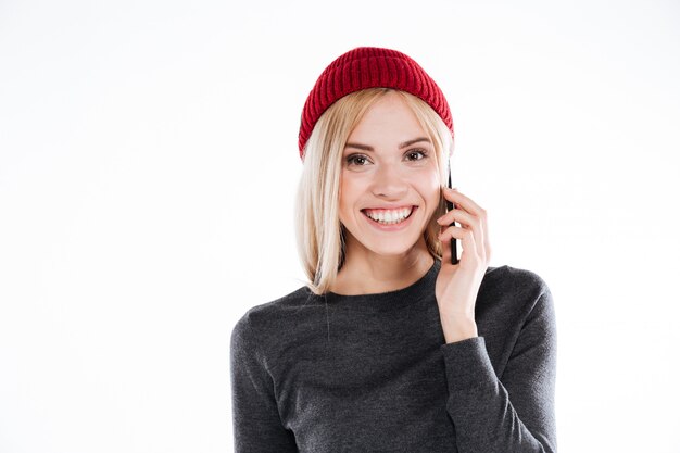 Smiling pretty young woman in hat talking on mobile phone