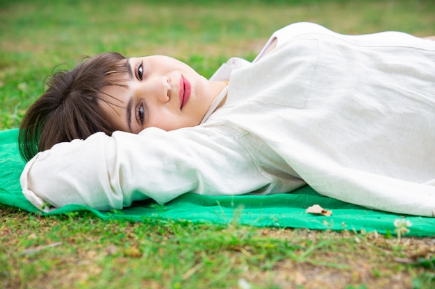 무료 사진 거짓말을하고 잔디밭에서 휴식 웃는 예쁜 젊은 여자