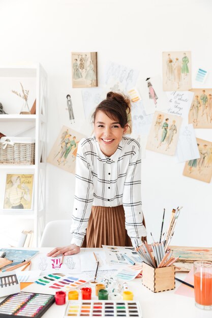 Smiling professional woman designer leaning at her work desk