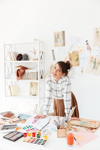 그녀의 작업 책상에 기대어 웃는 전문 여성 디자이너
