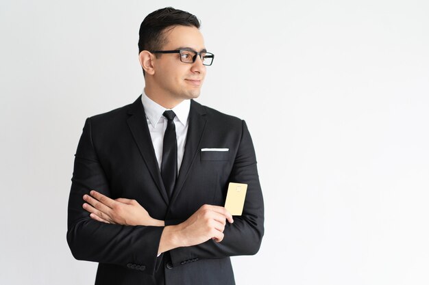 Smiling purposeful young businessman with credit card looking aside. 