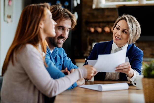 Smiling real estate agent communicating with a couple during a meeting at their home