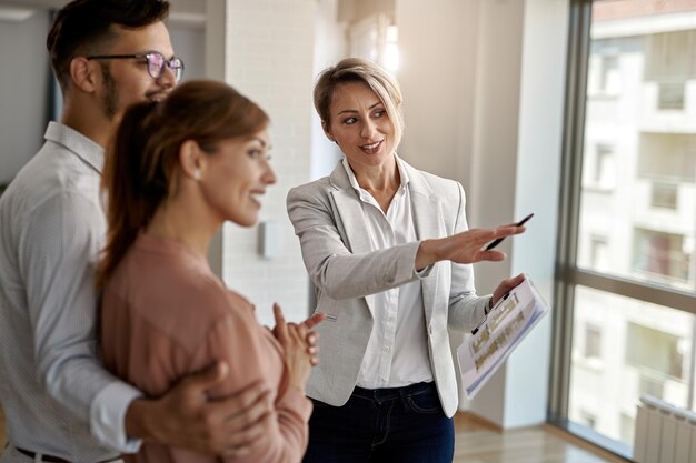 Smiling real estate agent talking with a couple interested in buying a new home