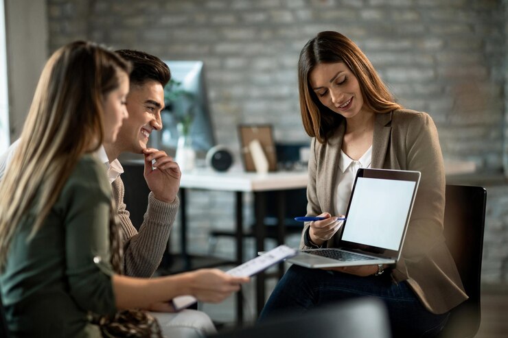 Free Photo smiling real estate agent using a computer while having a meeting with young couple and making investment plans