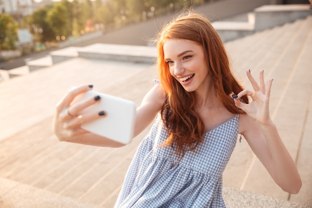 Selfieを取って長い髪の笑顔の赤毛の女性