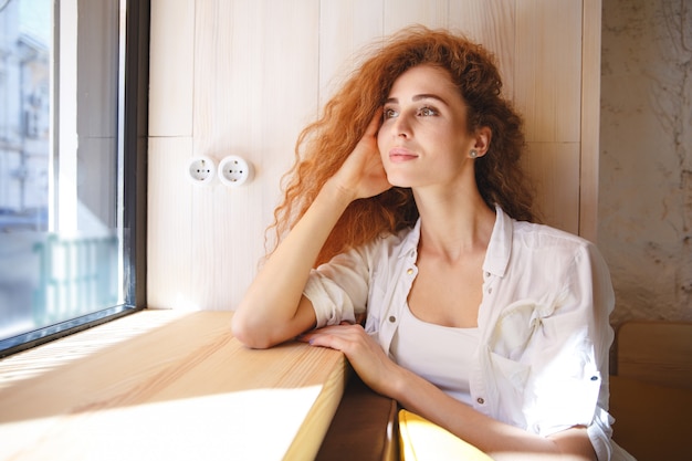 無料写真 カフェに座っている笑顔の赤毛の若い女性