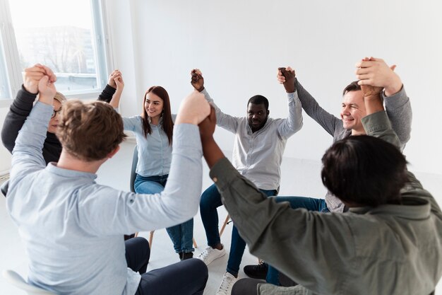 Smiling rehab patients raising hands and looking at each other