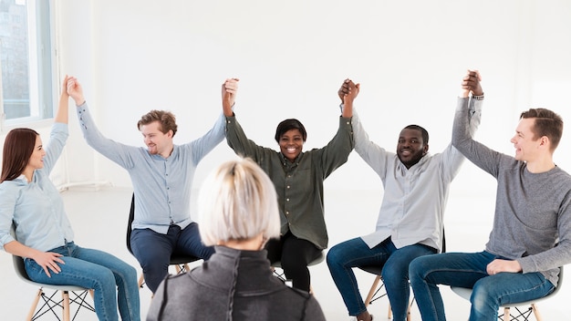 Smiling rehab patients raising hands