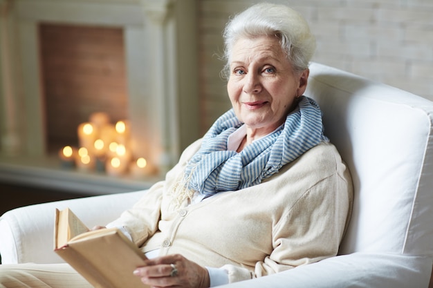 Улыбающаяся пенсионерка читает книгу