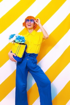 Smiling retro lady on trend striped yellow background with flower arrangement in her hands. minimal spring summer concept
