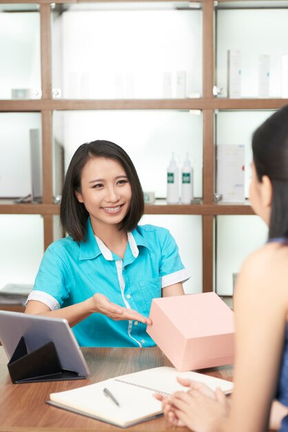 Smiling salon administrator giving present to client