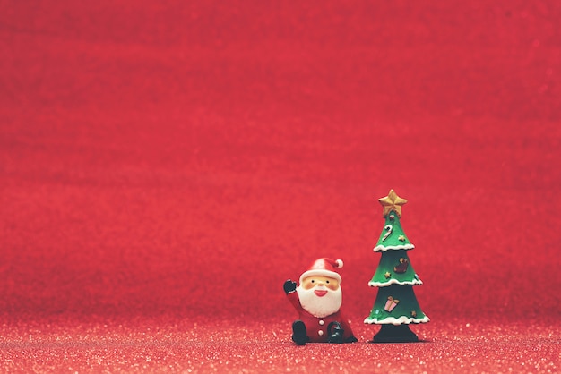 クリスマスツリーと赤の背景の隣にサンタクロースを笑顔