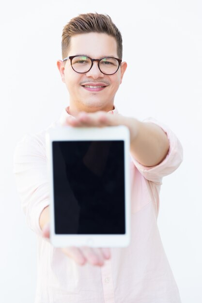 Smiling satisfied guy in eyeglasses showing blank tablet screen