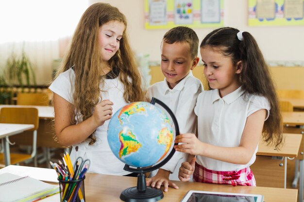 Smiling schoolchildren examining globe