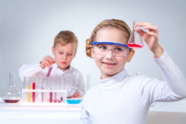 Smiling schoolgirl holding a flask with red liquid