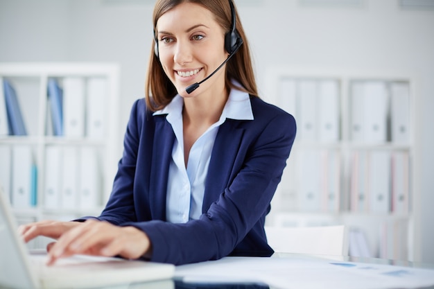 Smiling secretary typing on laptop